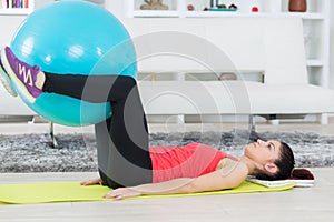 Fit young woman holding exercise ball between legs