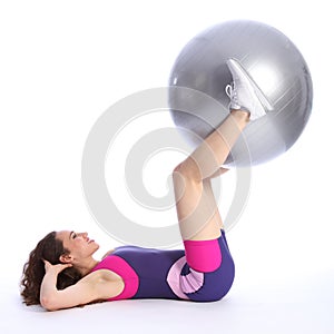 Fit young woman lifts exercise ball with legs