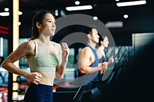 Fit young woman and man running on a treadmill during a workout class