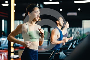 Fit young woman and man running on a treadmill during a workout class