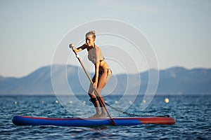 Fit young woman paddling on sup board