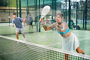 Fit young woman playing padel tennis on open court