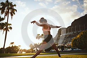 Fit young woman practicing yoga in a city park