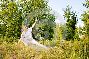 Fit young woman practicing yoga on park outside the city. Meditative lady enjoying meditation