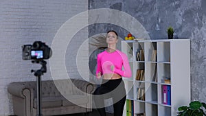 Fit young woman in sportswear running on spot at home while doing cardio workout training, using camera on tripod to