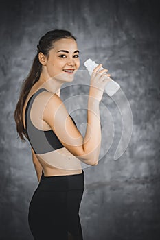 Fit young woman standing and drinking milk in bottle after workout or exercise in gym. Woman at gym taking a break and relax