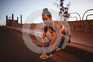 Fit young woman tying her running shoes before a run