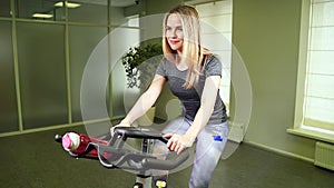 Fit young woman using bike at the gym. Strong female athlete doing cardio workout on cycle at health club.