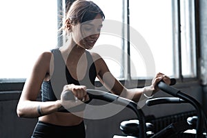 Fit young woman using exercise bike at the gym. Fitness female using air bike for cardio workout at gym