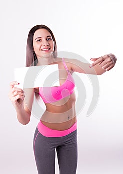 fitnes brunette in a tracksuit holding empty white board