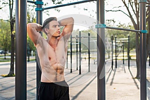 Fitnes man posing on street fitness station showing his muscular body