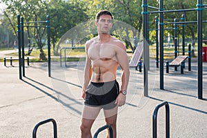 Fitnes man posing on street fitness station showing his muscular body