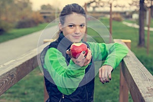 Fitnes trainer offering an apple at outdoor gym.
