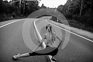 An fitnes woman warm-up before jogging on the country road. Black and white photo.