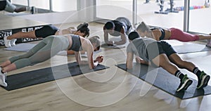Fitness, active and sporty group doing plank exercise, endurance training and body muscle workout inside a gym. Diverse