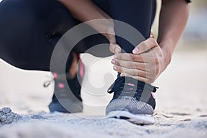 Fitness, ankle pain and running with woman on beach for sports injury, inflammation and accident. Emergency, healthcare