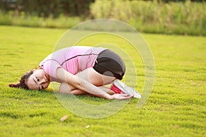 Fitness Asian Chinese woman have a rest at grass in a park