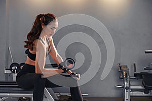 Fitness asian woman doing exercise and lifting dumbbells weights at sport gym