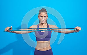 Fitness asian woman in sportswear exercising with a resistance band on blue background. Attractive active female doing squatting