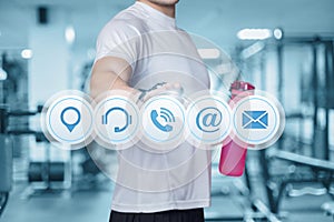 Fitness athlete clicks on the contact icons on the background of the gym