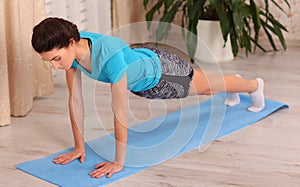 Fitness athlete sportive woman sport model girl training crossfit doing push ups plank at home.