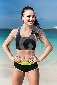 Fitness athlete woman in sportwear standing on the beach