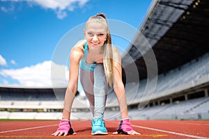 Fitness athletic girl preparing for a run on sport track at stadium. Healthy and sporty lifestyle with young girl running