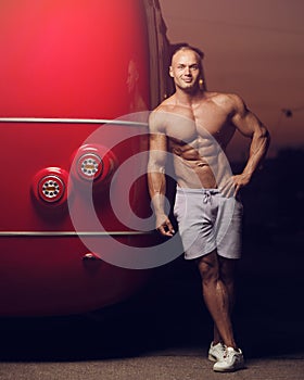 Fitness athletic man at street near red bus