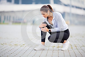 Fitness. Athletic women holding knee having a trauma