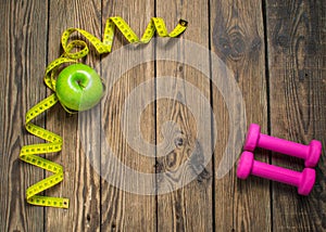 Fitness background with dumbbells, green apple and measuring. Healthy lifestyle concept with copy space