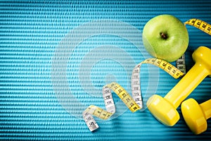 Fitness background with dumbbells, measuring tape and apple. Healthy lifestyle concept