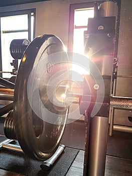 Fitness barbell against the sunlight with lensflare.