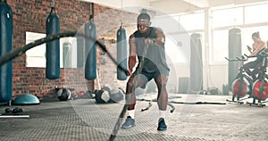 Fitness, battle ropes or black man training in workout for wellness at gym with resilience or power. Hard work, energy