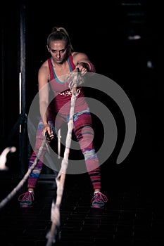 Fitness battling ropes at gym workout fitness exercise.Young woman doing some crossfit exercises with a rope at a gym