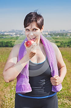 Fitness beautiful plus size woman eating apple