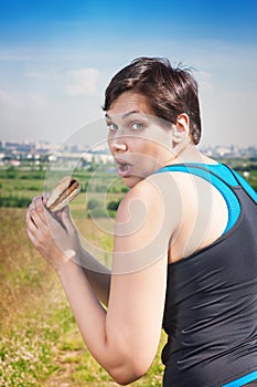 Fitness beautiful plus size woman stealthily eating junk food photo