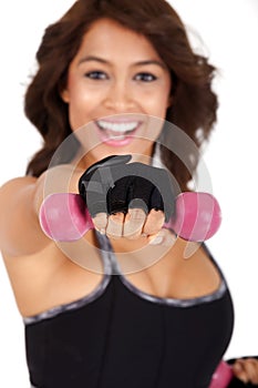 Fitness: Beautiful and very athletically fit woman curls dumbbells with a winning smile.