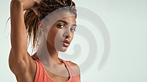 Fitness beauty. Close up of beautiful young african woman in sportswear holding her hair in hand and looking at camera