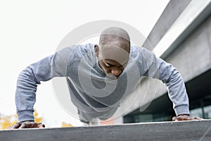 Fitness black man exercising push ups in urban background