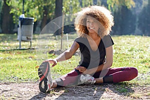 Fitness black woman runner stretching legs after run