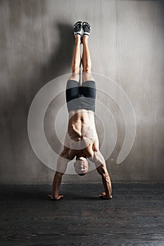 Fitness body, wall and man doing handstand for muscle workout, balance focus or health club exercise. Gym training, hand