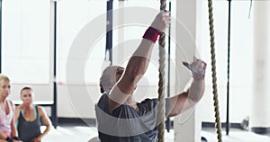 Fitness, bodybuilder and man climb rope for exercise, weightlifting and intense training in gym. Sports, challenge and