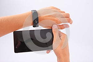 Fitness bracelet and phone in female hands on white