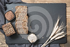 Fitness bread. A loaf of fresh rustic whole rye bread with wheat, sliced on a black slate dish and board, rural food background. T