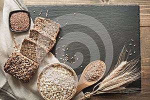 Fitness bread. A loaf of fresh rustic whole rye bread with wheat, sliced on a black slate dish and board, rural food background. T