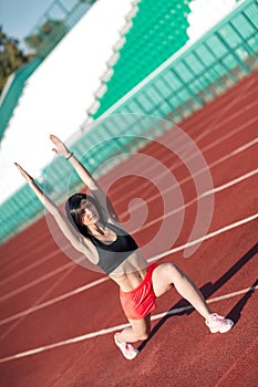 Fitness brunette woman in pink shorts and tank top doing lunges exercises for leg muscle workout training, outdoors. Active girl