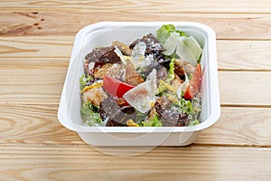 Fitness Caesar salad with chicken. Healthy food. Takeaway food. On a wooden background