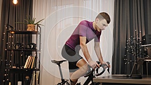 Fitness cardio workout. Man cyclist is cycling training on indoor smart trainer at home. Fit sportive male athlete is pedaling on