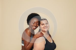 Fitness. Caucasian And African Women Portrait. Different Race Models In Fitness Clothes Posing On Beige Background.