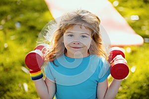 Fitness child boy raising a dumbbell. Cute child training with dumbbells. Children fitness. Kid boy exercising with